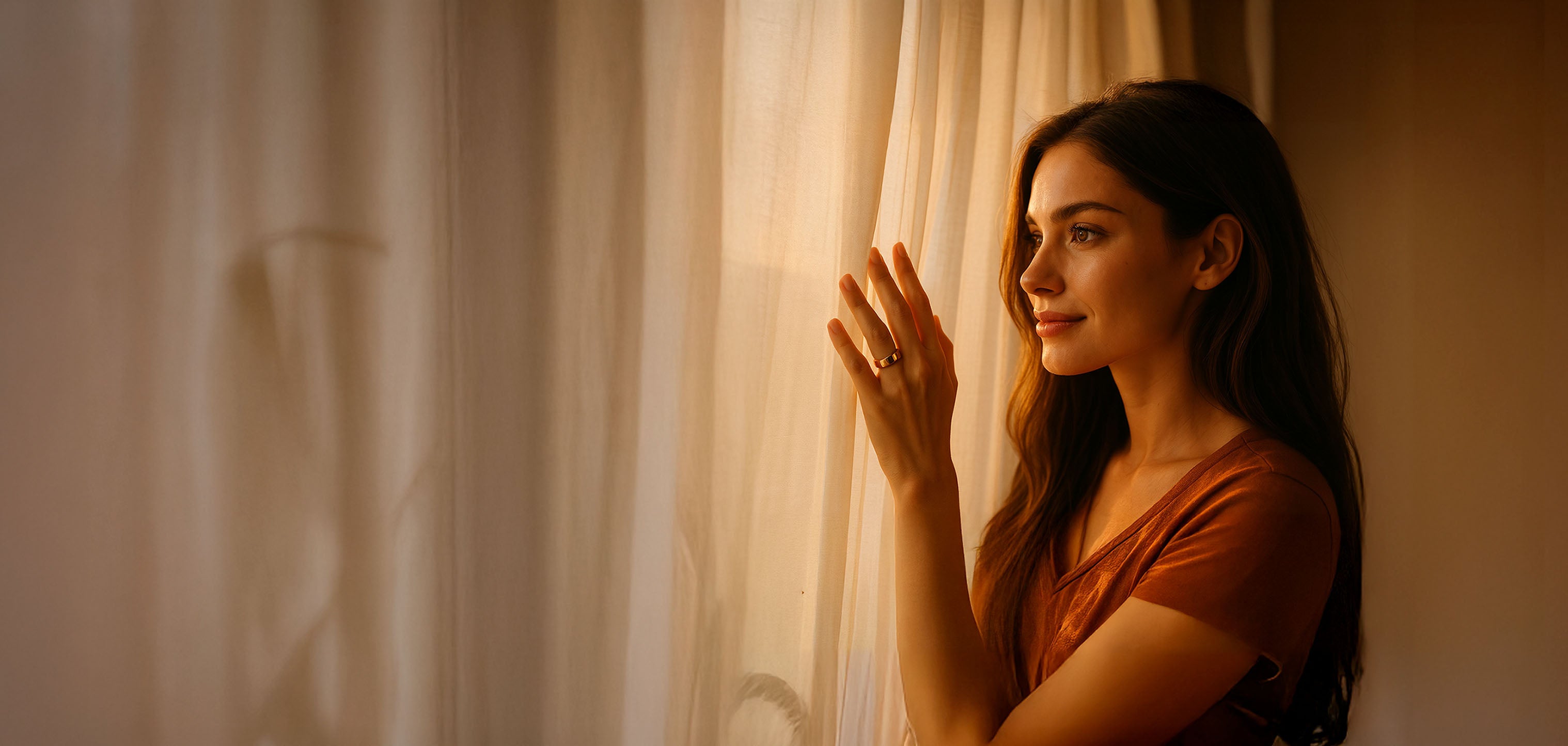 Woman standing behind a curtain in a warm, softly lit room