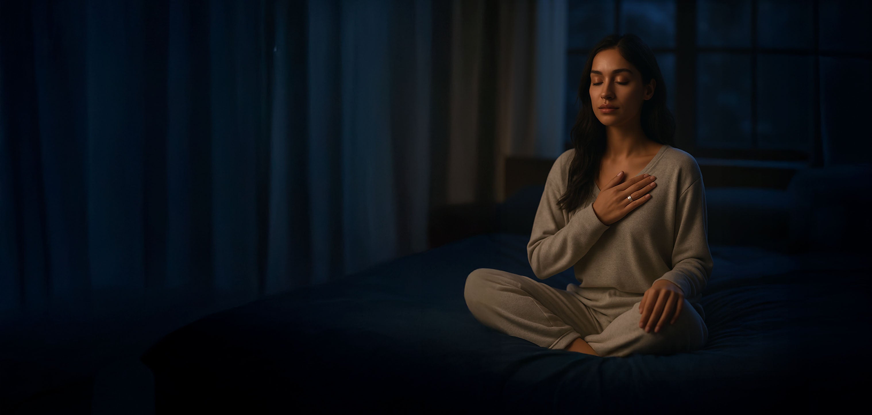 Woman meditating in a dark room wearing calmara ring